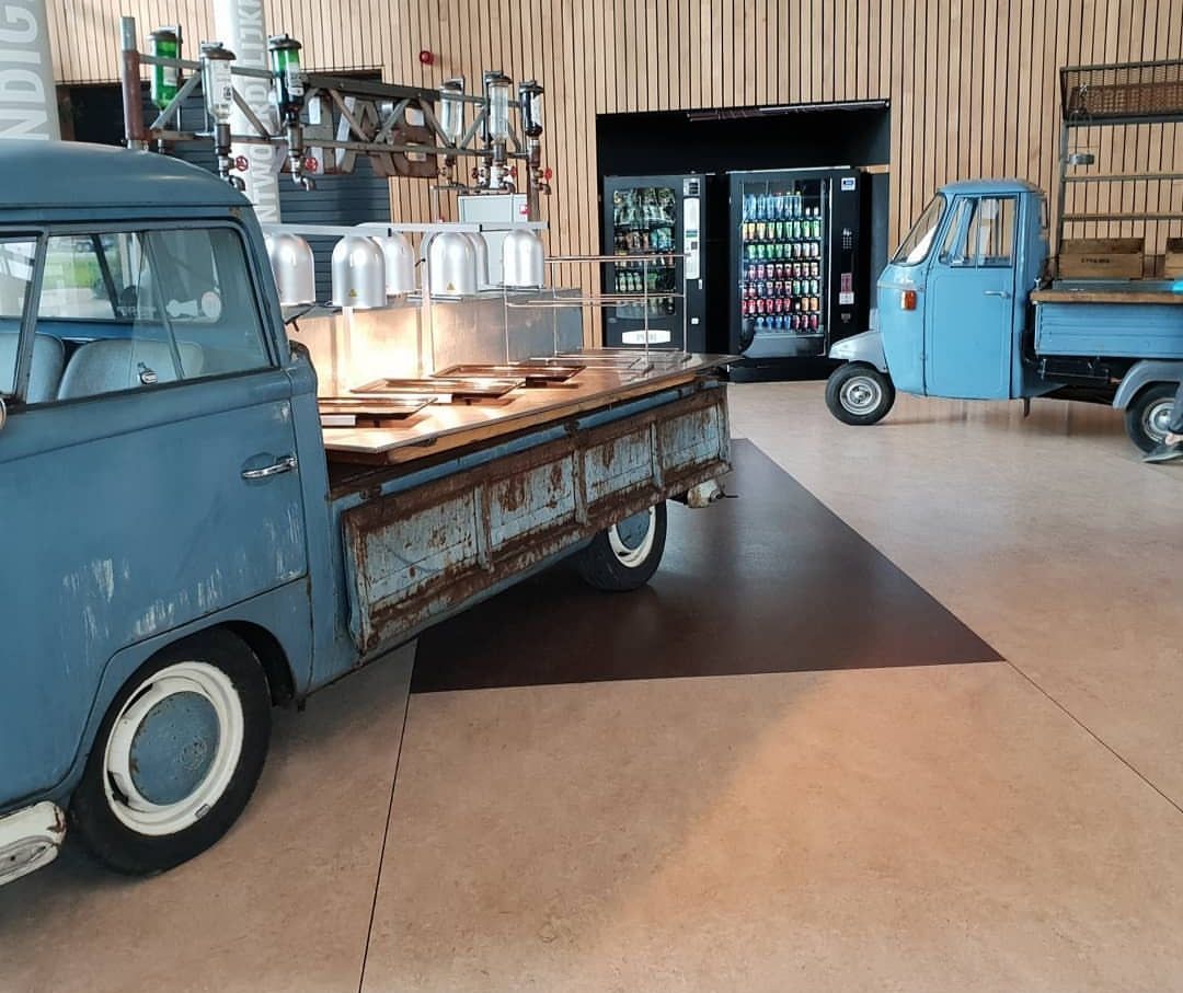 Een blauwe vintage pick-up truck met een voedselbuffet in een café in pakhuisstijl.