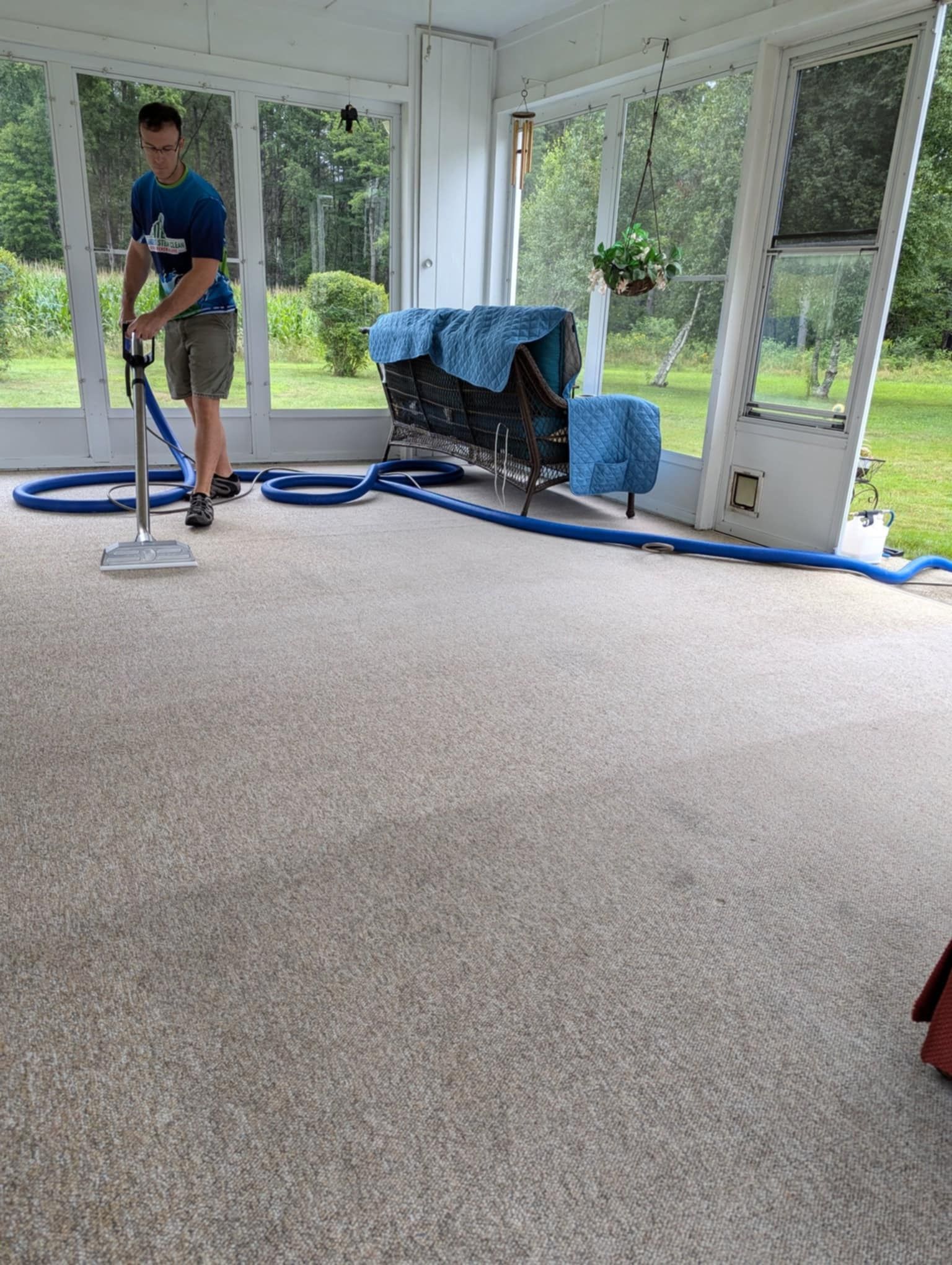 A man is using a vacuum cleaner to clean a carpet in a room.