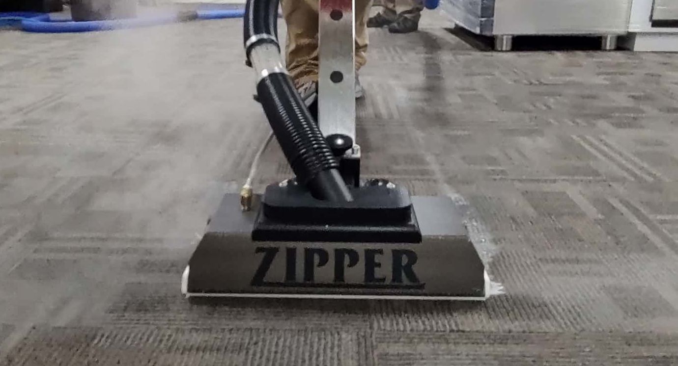 A person is using a zipper vacuum cleaner to clean a carpet.