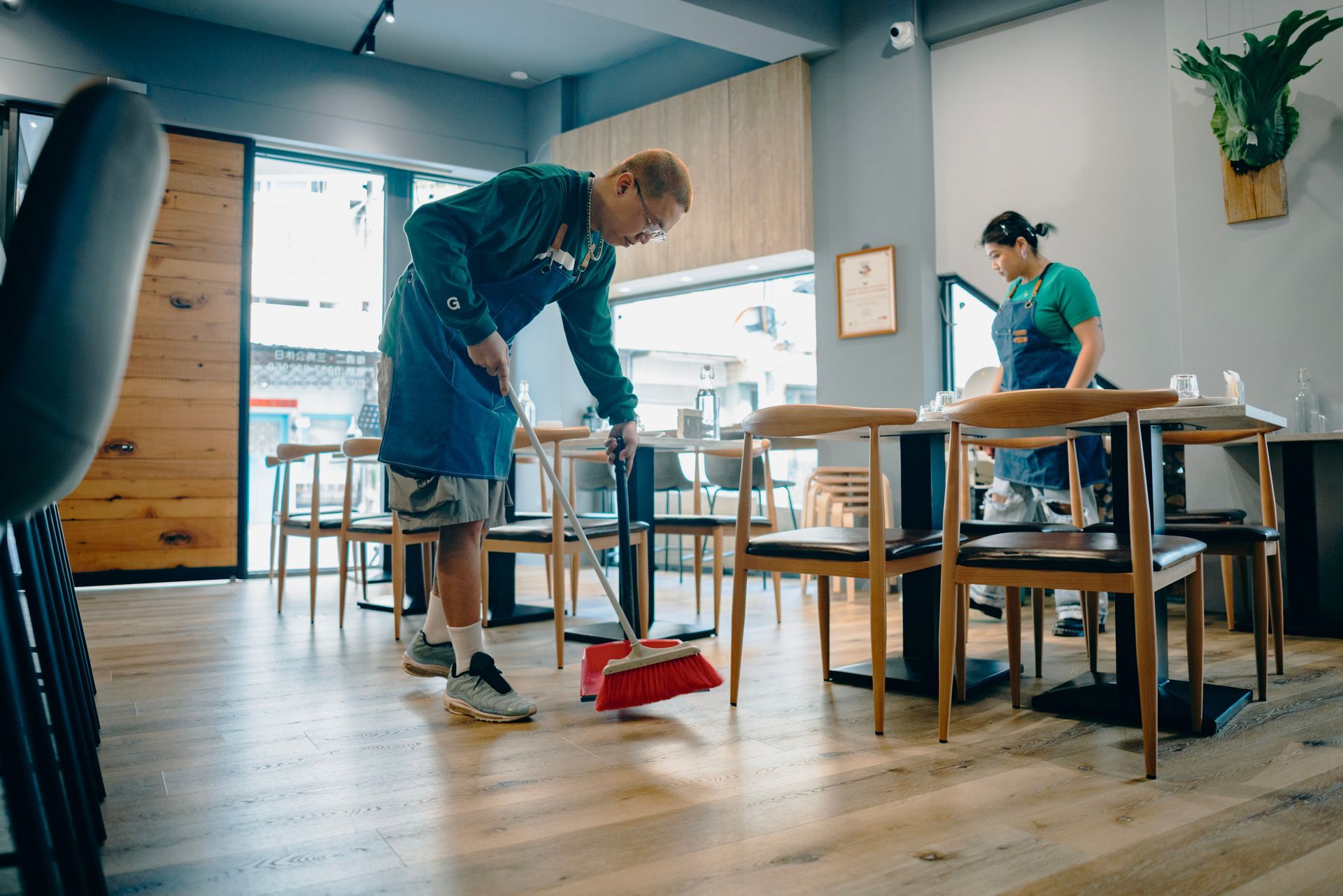 A man is sweeping the floor of a restaurant with a broom from Flanders Cleaning Services a local commercial cleaning company.