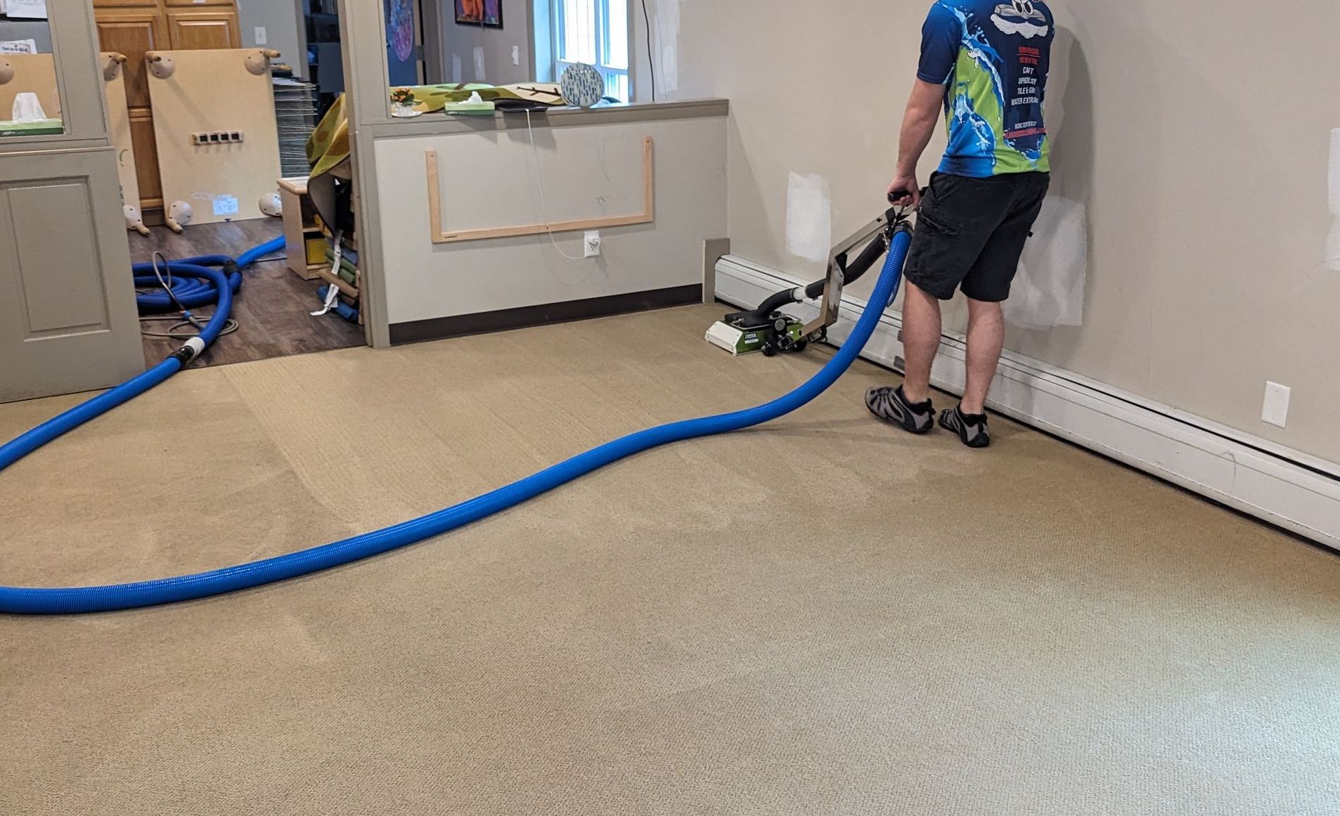 A man is using a vacuum cleaner to clean a carpet in a room.
