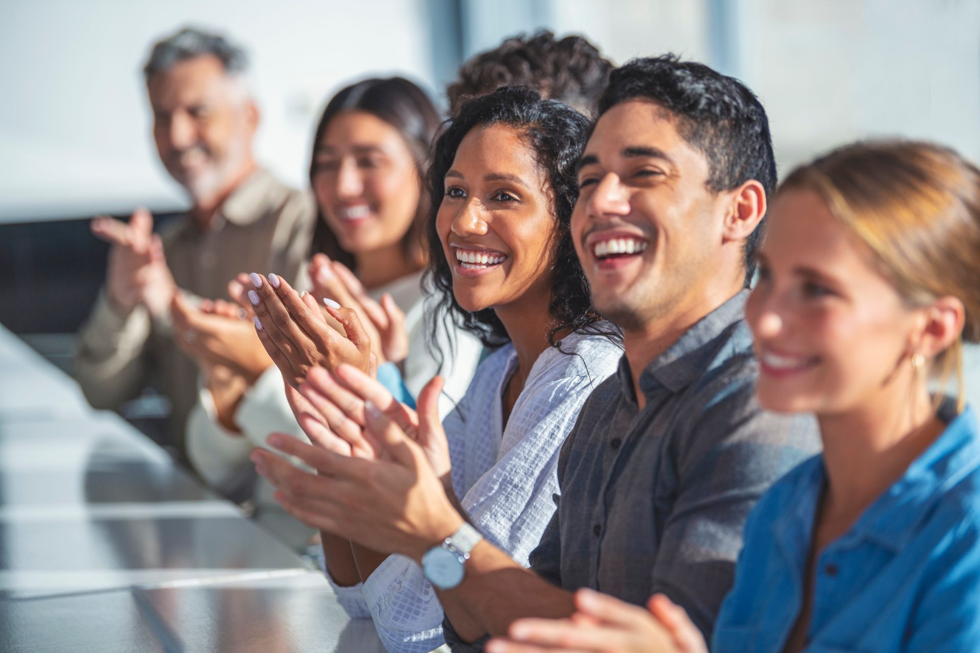 A group of people are sitting in a row clapping their hands.
