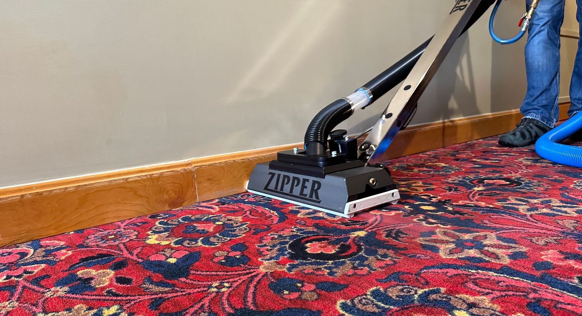 A zipper vacuum is being used to clean a rug