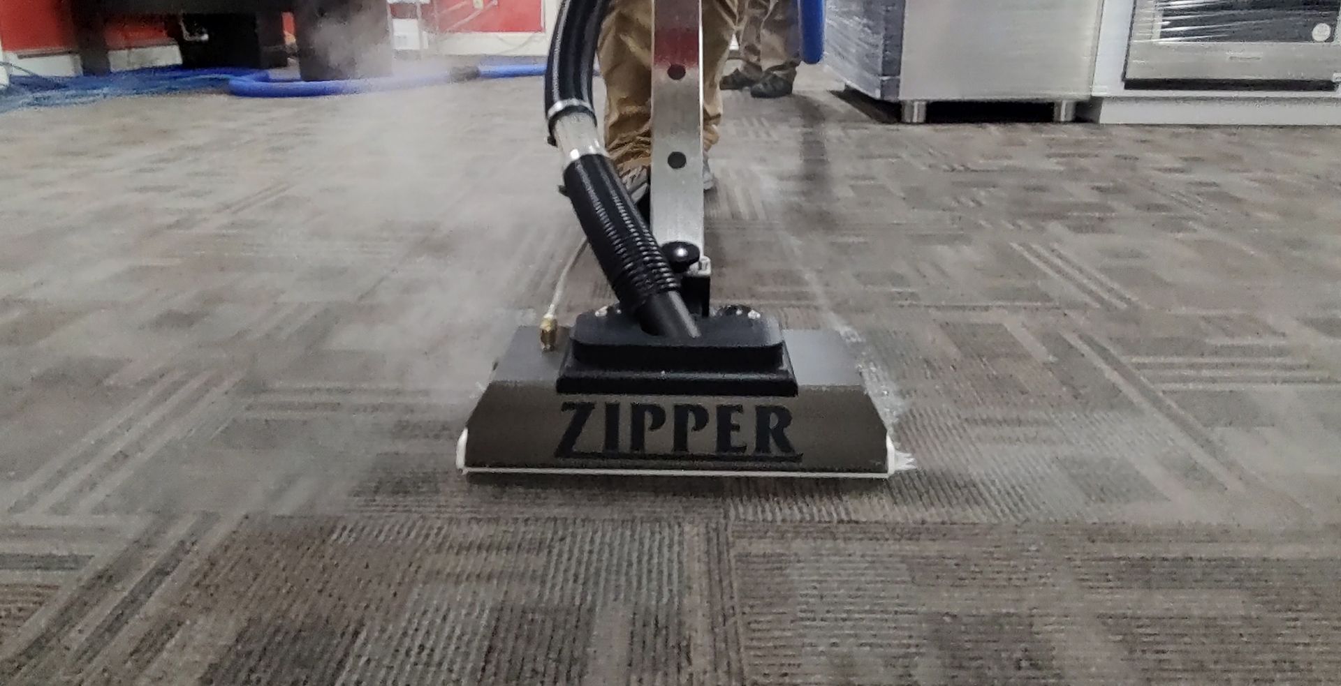A person is using a zipper vacuum cleaner to clean a carpet cleaned by Flanders carpet cleaning services