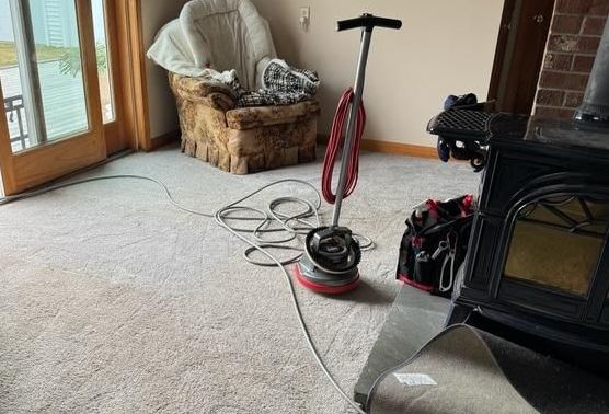 A vacuum cleaner is sitting on a carpet in a living room next to a fireplace.