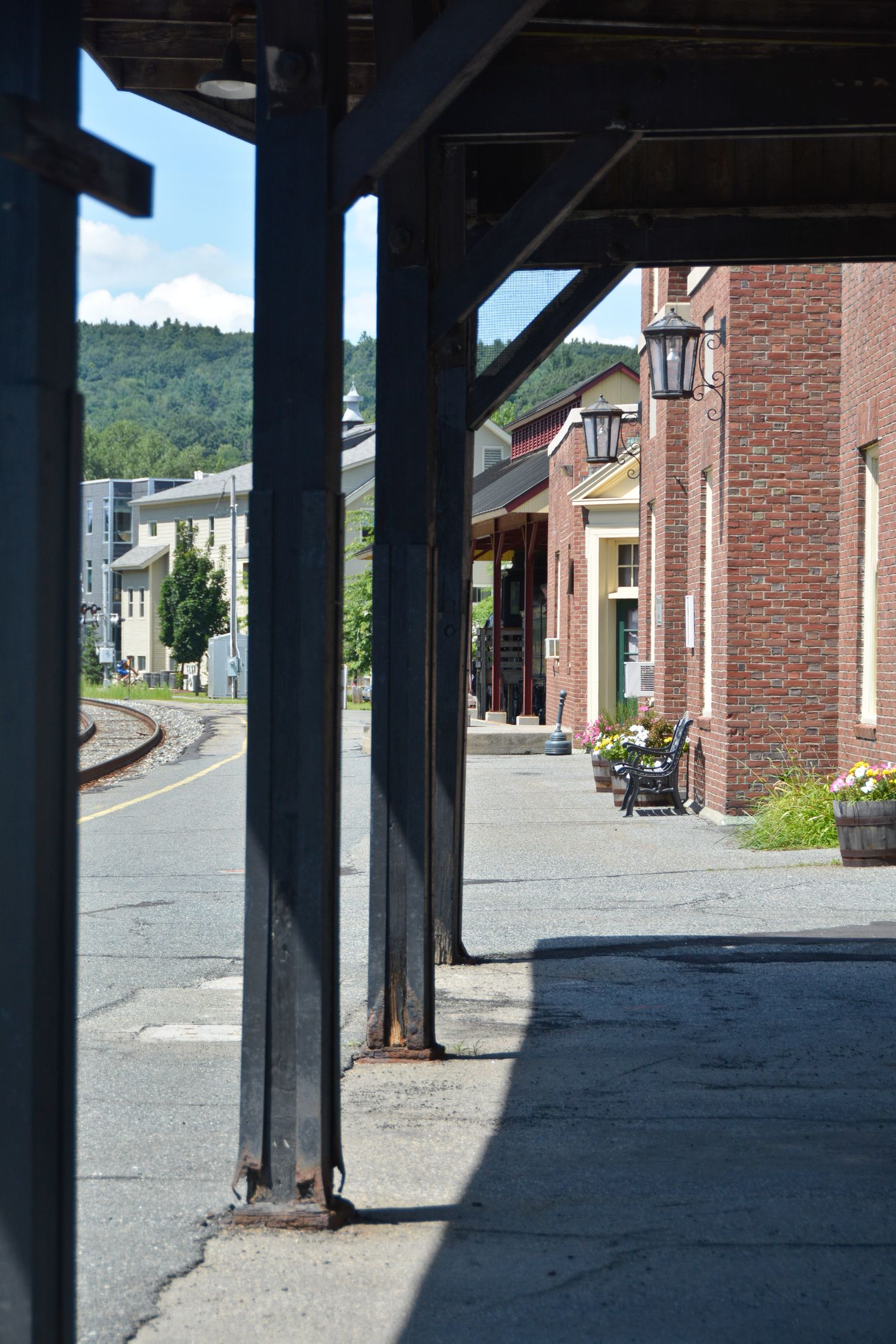 Covered walkway beside a brick building along a gravel railway path