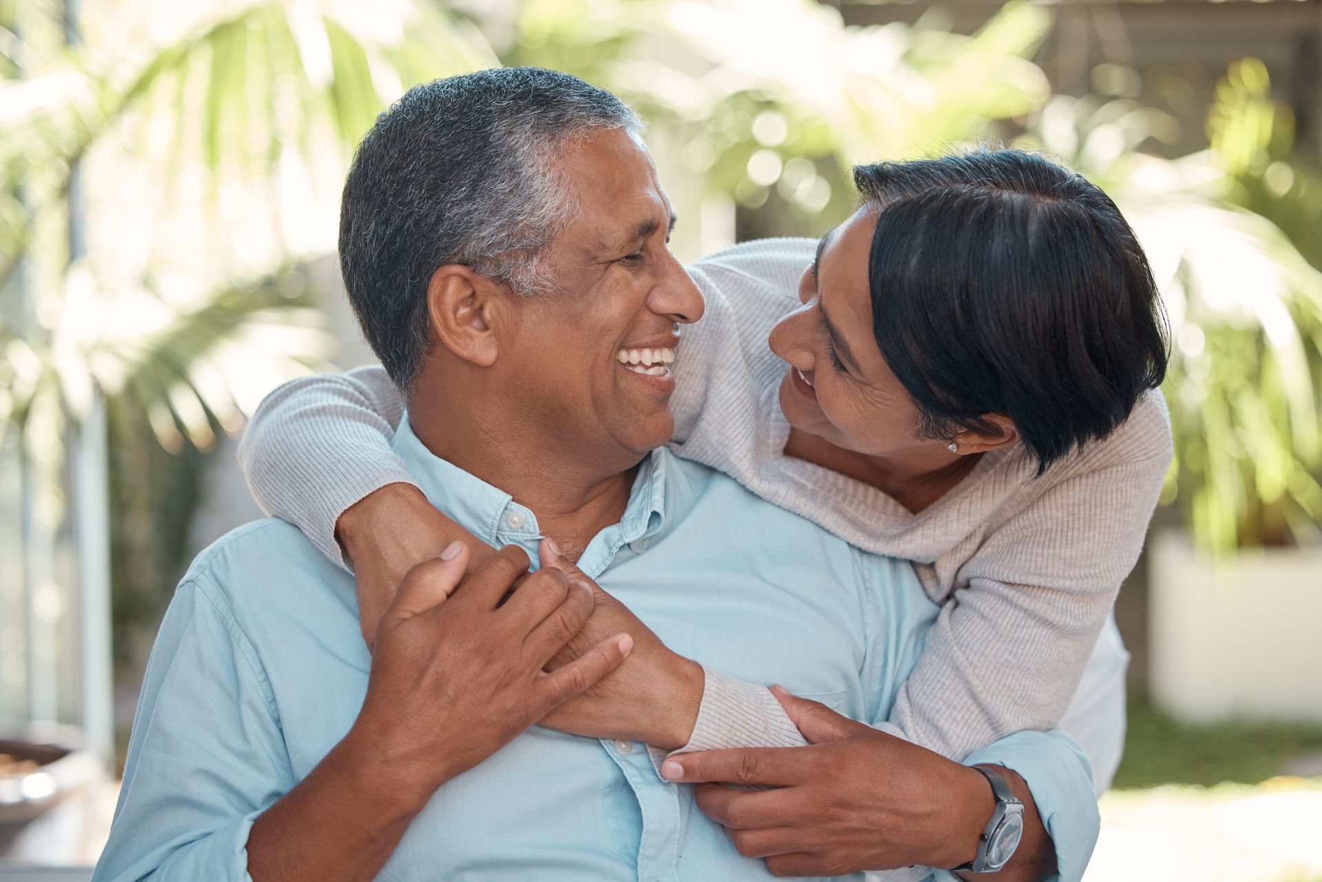 Two people smiling and hugging outdoors in a bright garden