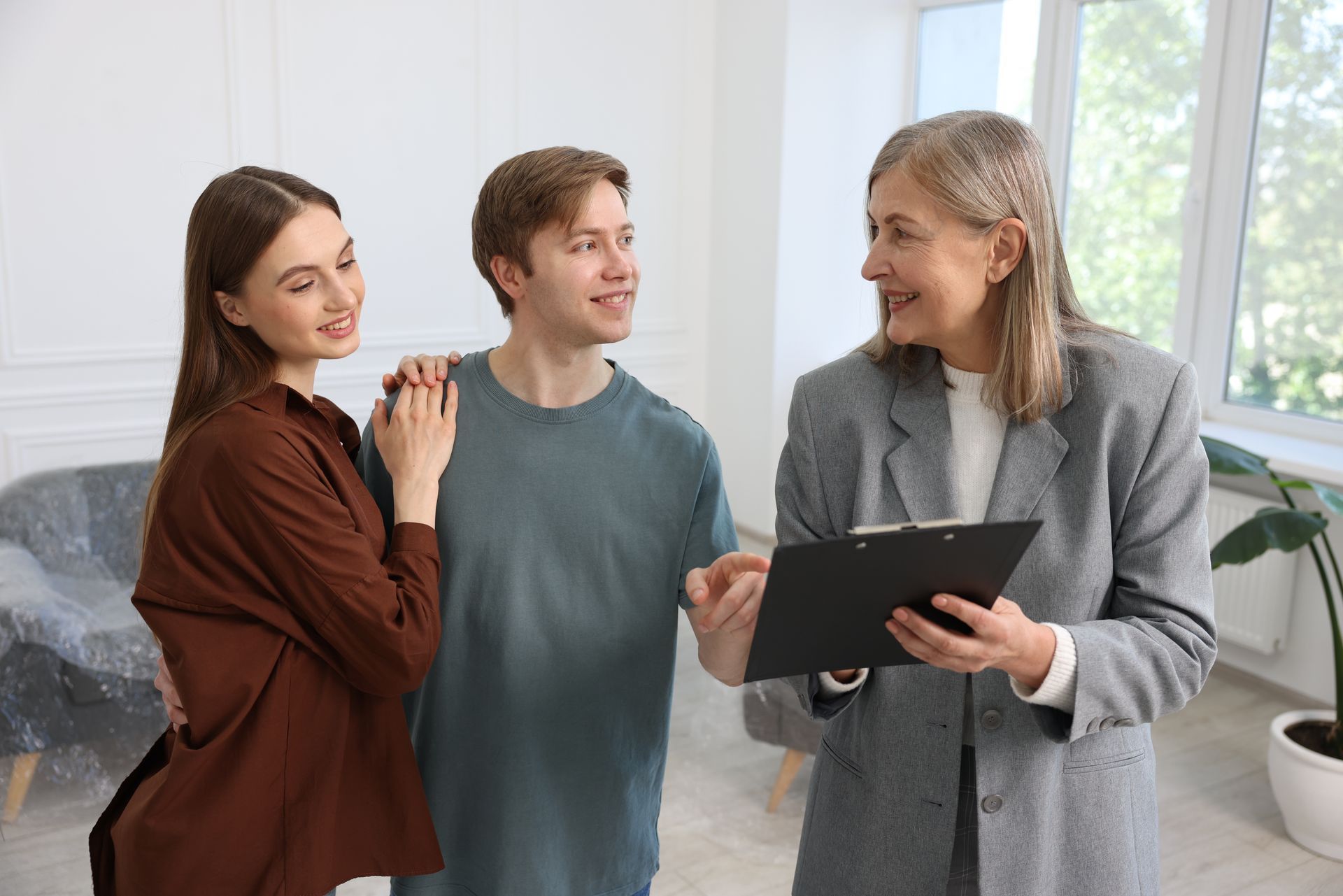 Three people discussing a tablet in a bright living room