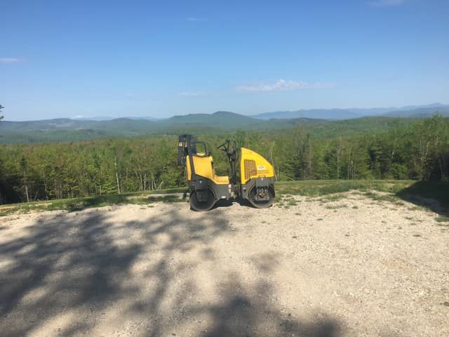 A yellow tractor is parked on the side of a dirt road.