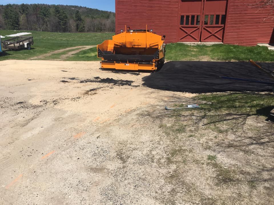 An orange tractor is parked in front of a red barn