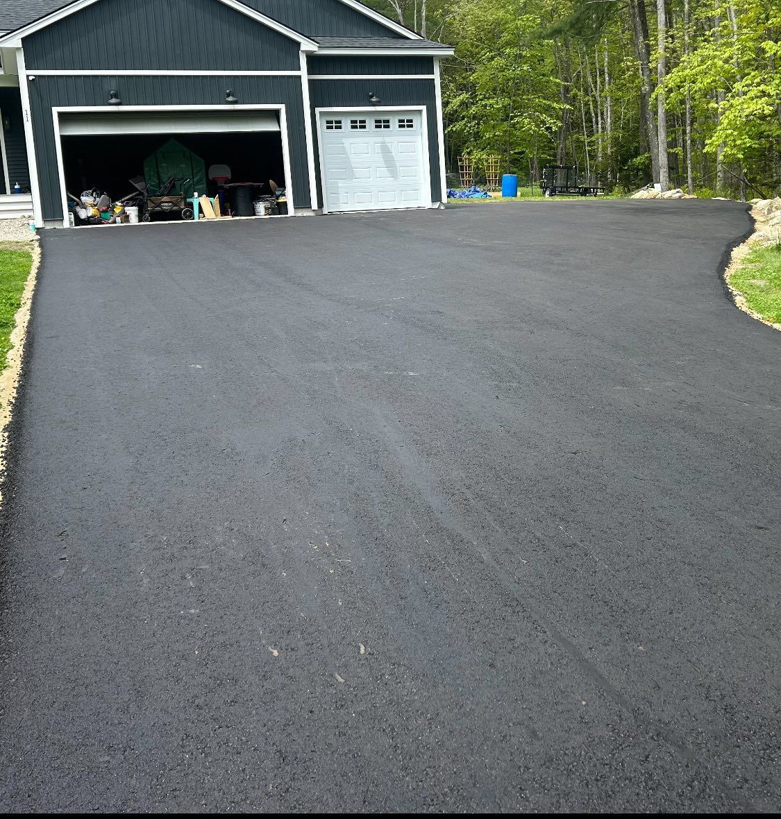 A driveway leading to a black house with a white garage door