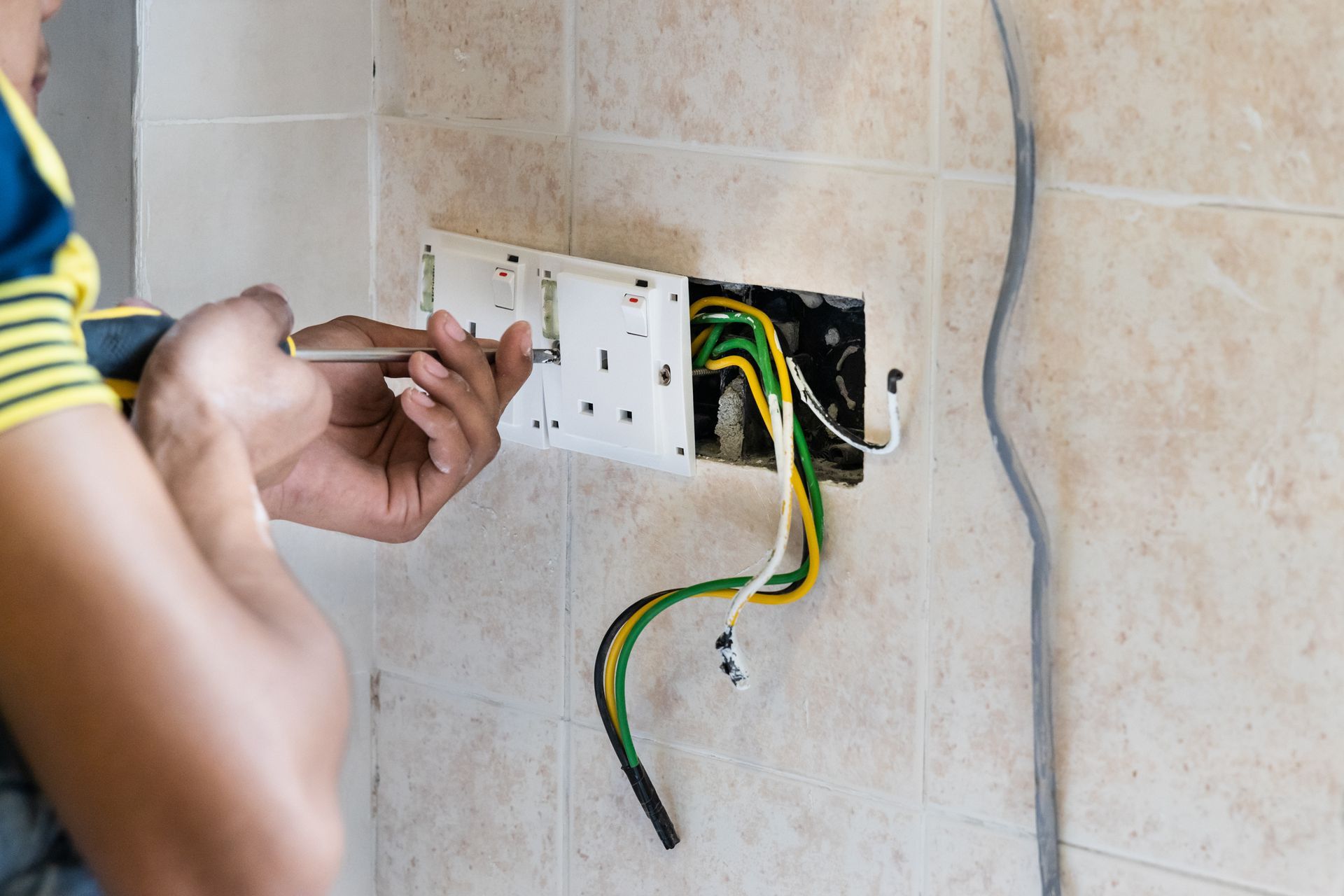 A man is installing an electrical outlet on a wall.