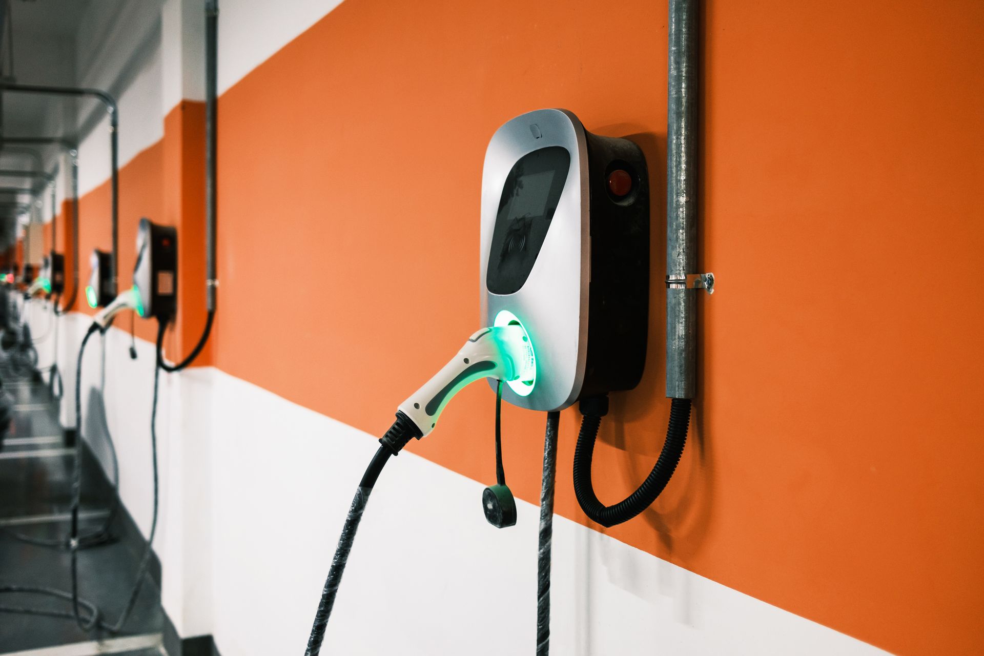 A row of electric vehicle charging stations on an orange and white wall.
