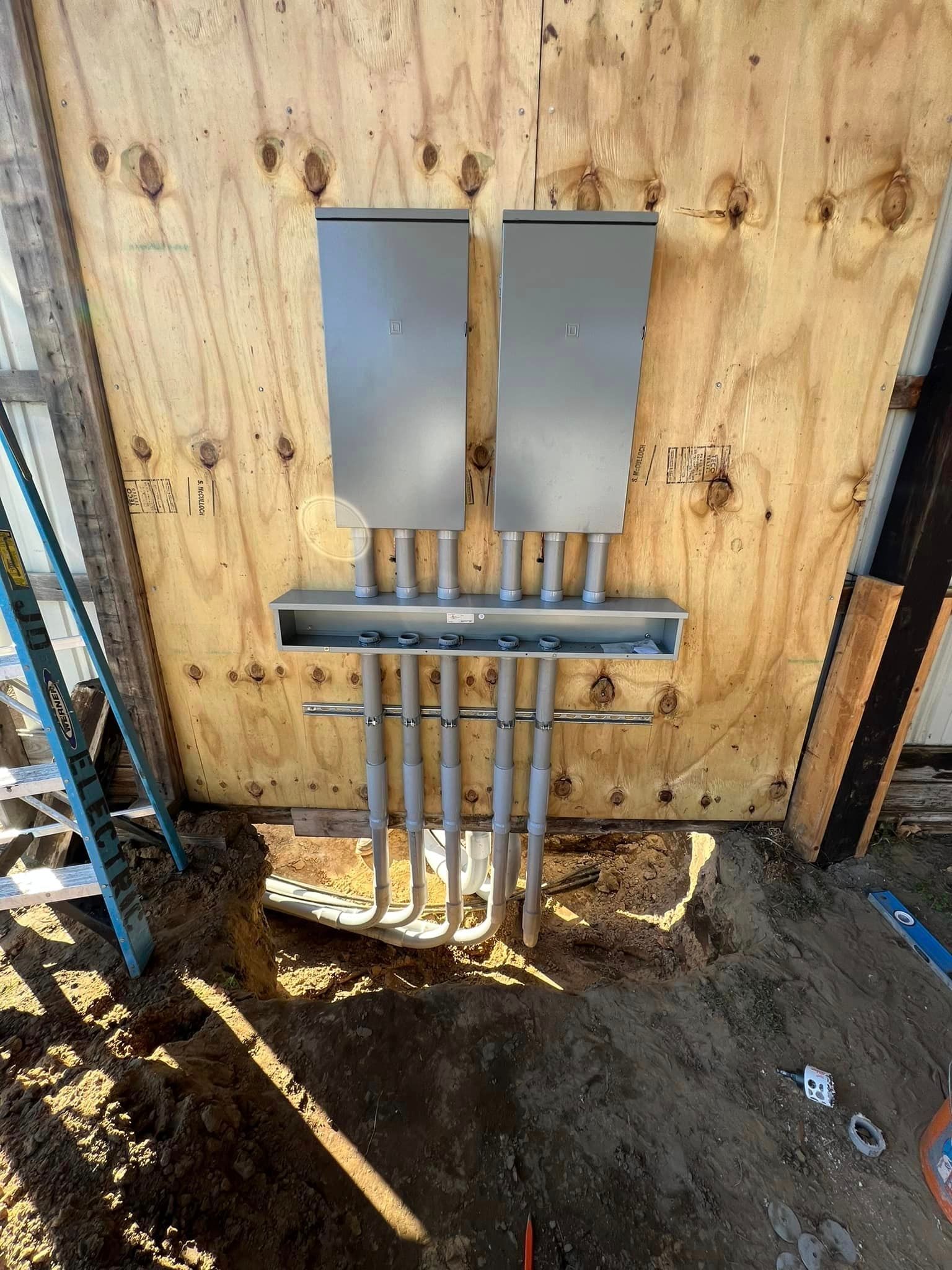 Electrical conduit and metal boxes mounted on plywood at a construction site