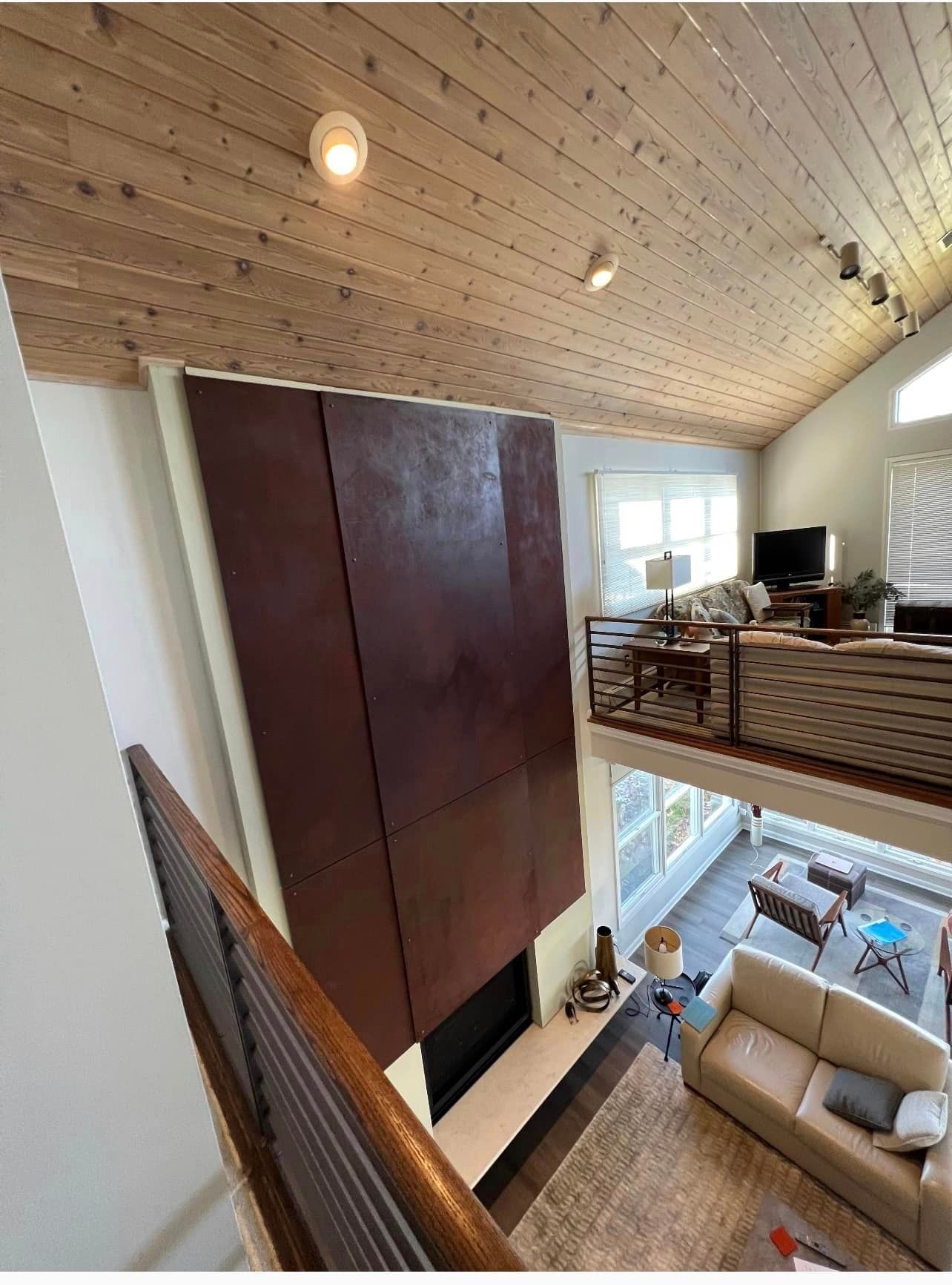 Loft living room with a large dark cabinet, white sofa, wooden ceiling, and open upstairs railing.