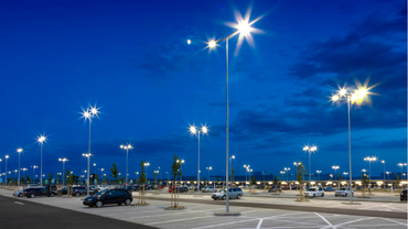 Empty parking lot at dusk with bright streetlights and a deep blue sky