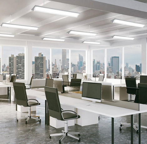 Modern open-plan office with white desks, green chairs, and large windows overlooking a city skyline