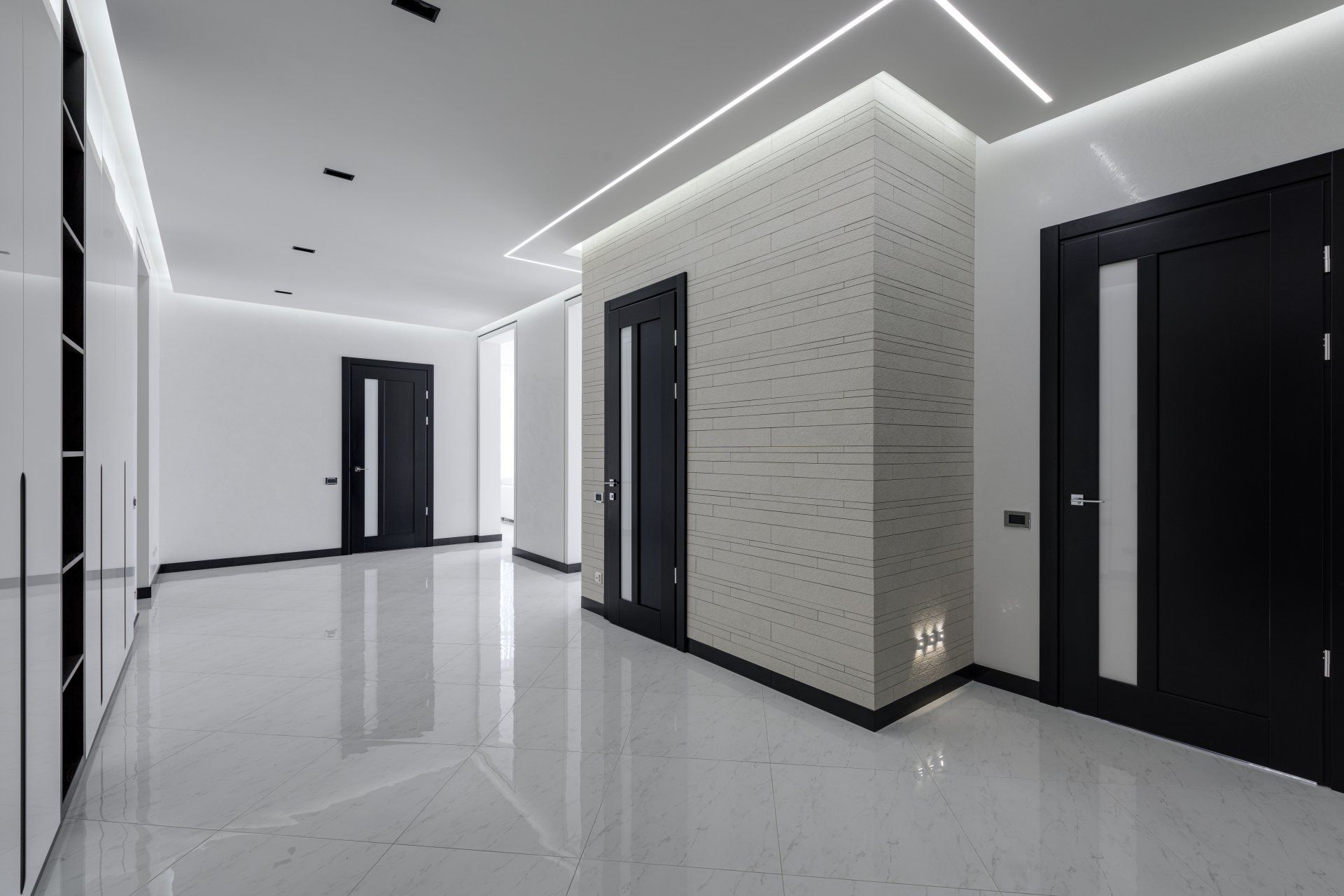 Modern apartment hallway with glossy floors, black doors, and white walls with recessed lighting