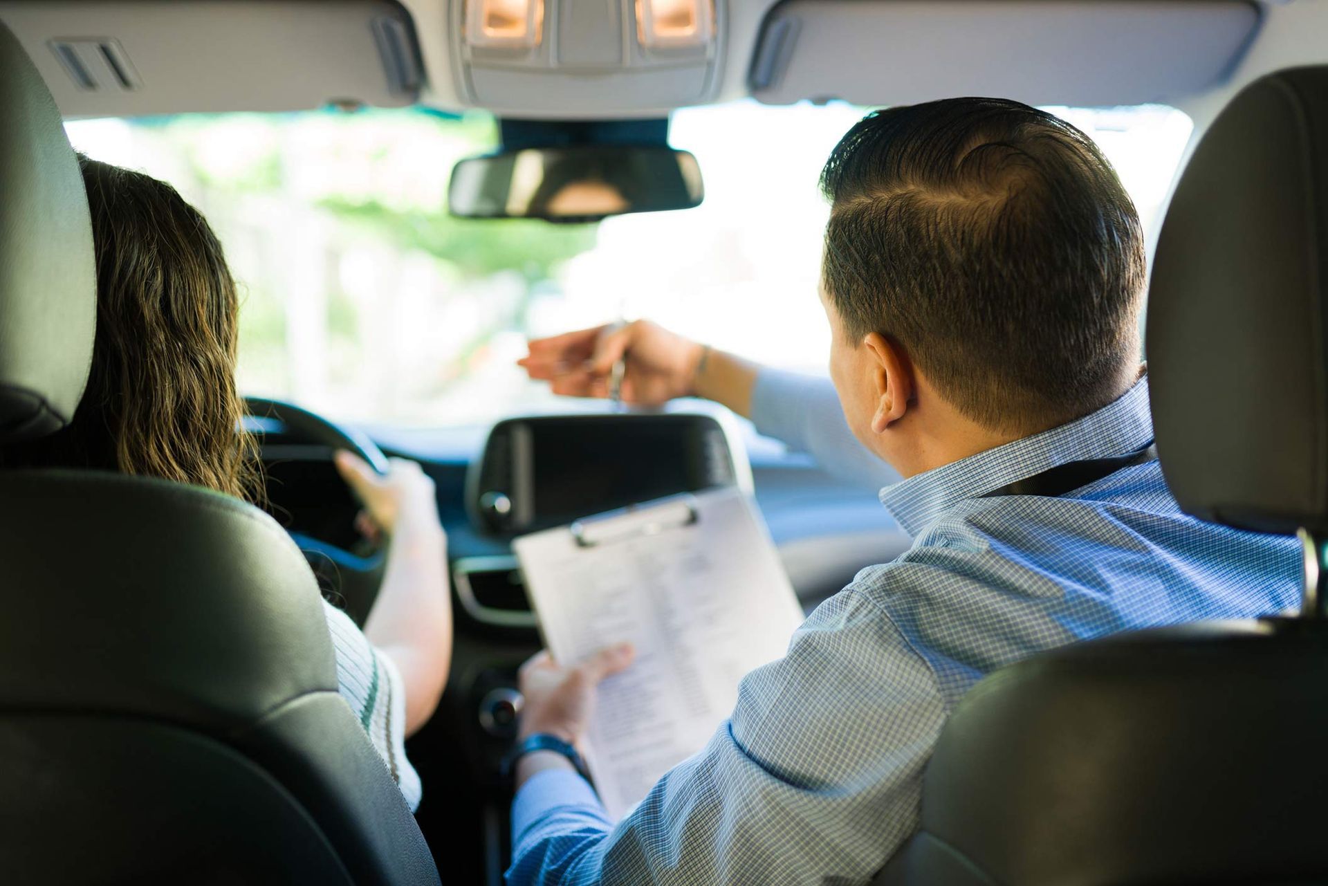 Driving instructor guiding teen student during driving test lesson. Driving instructor guiding teen student during driving test lesson.