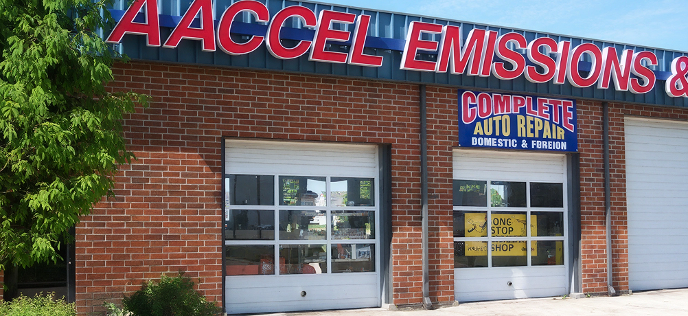 Storefront with red brick facade, garage bay door, and AACCEL Emissions & Complete Auto Repair sign | AACCEL Emissions & Auto Repair Specialists