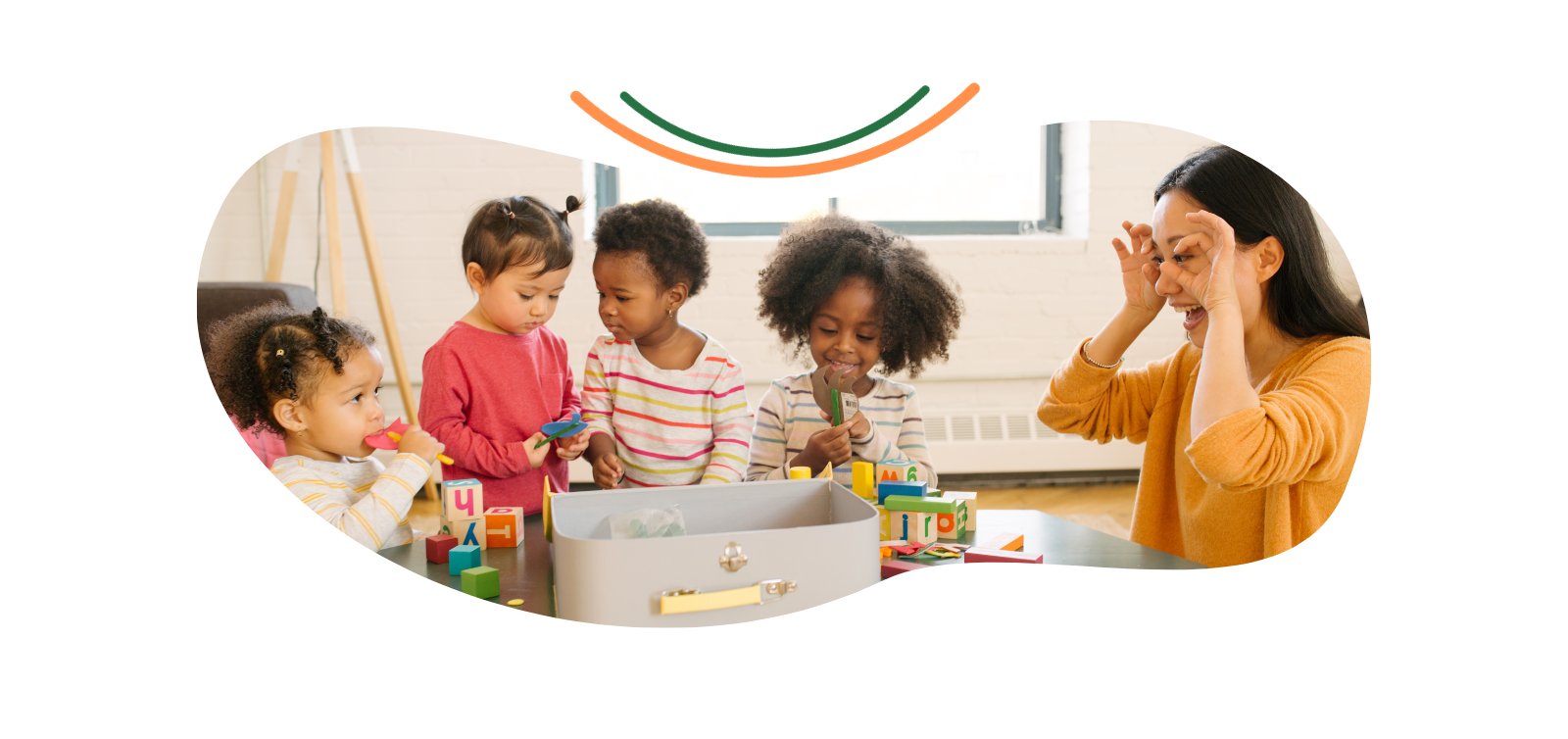 A woman is sitting at a table with a group of children playing with toys.