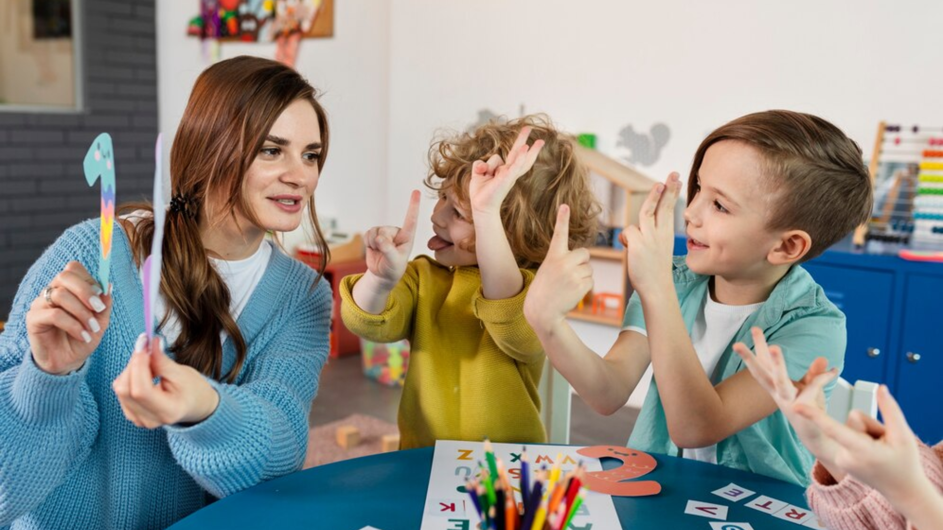 Teacher with students counting with fingers; one holds a number one. Preschool classroom setting.
