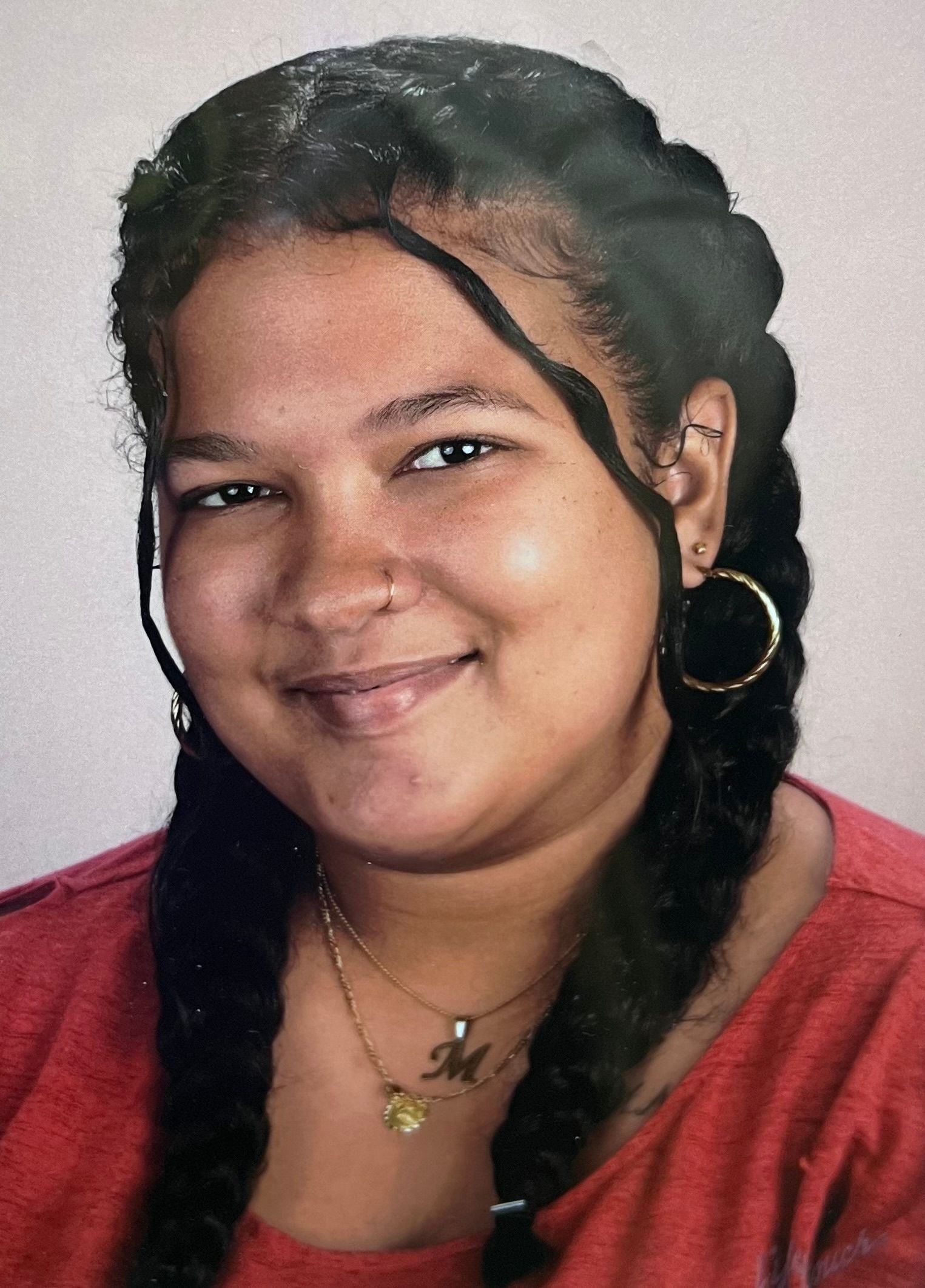 A woman wearing a red shirt and a necklace with the letter m on it