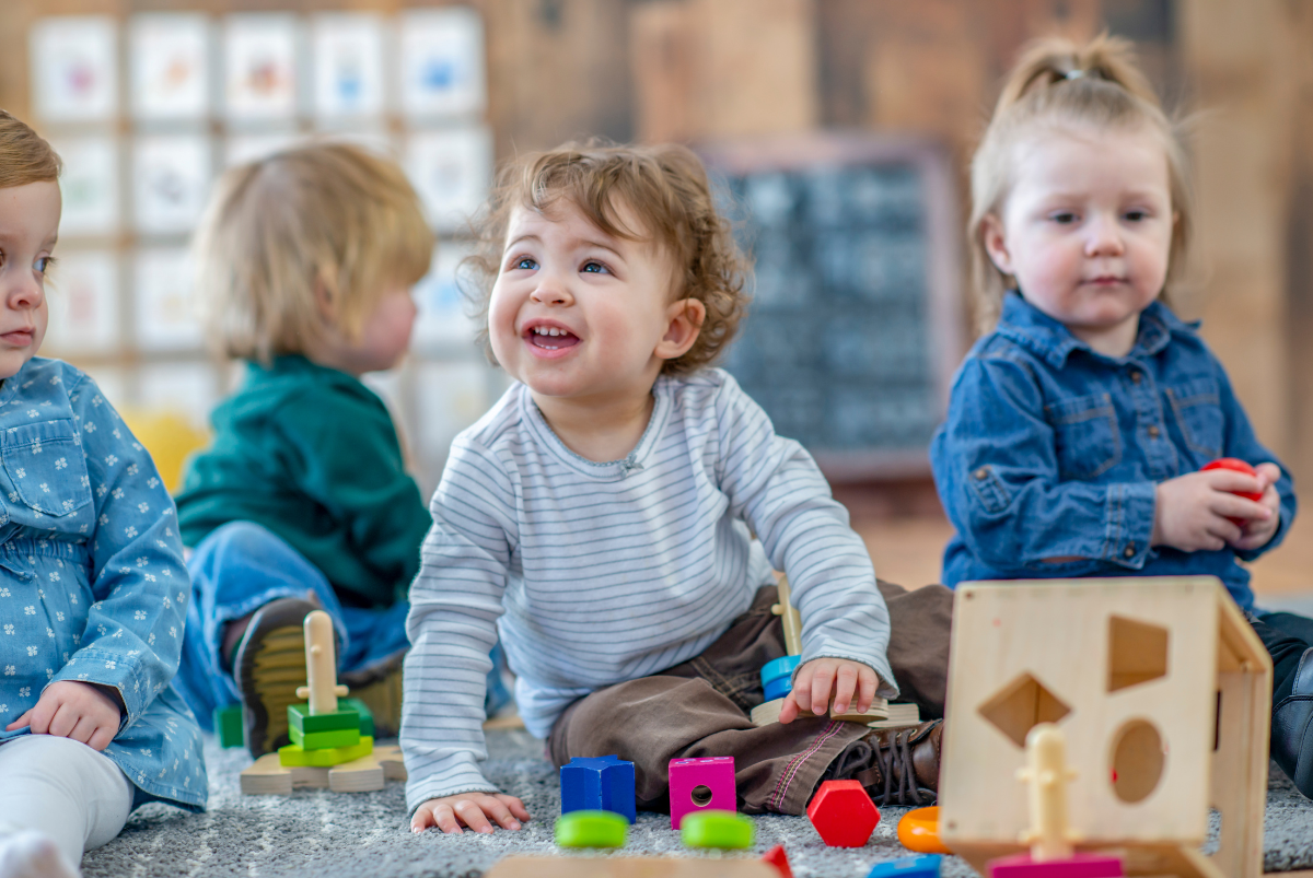 A group of young children are sitting on the floor playing with toys.