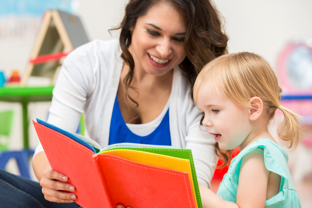 A woman is reading a book to a little girl.