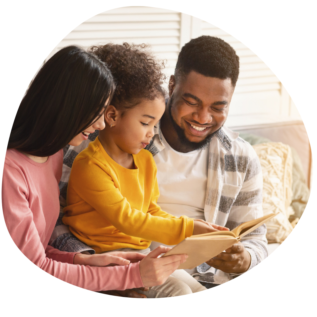 A family is sitting on a couch reading a book together.