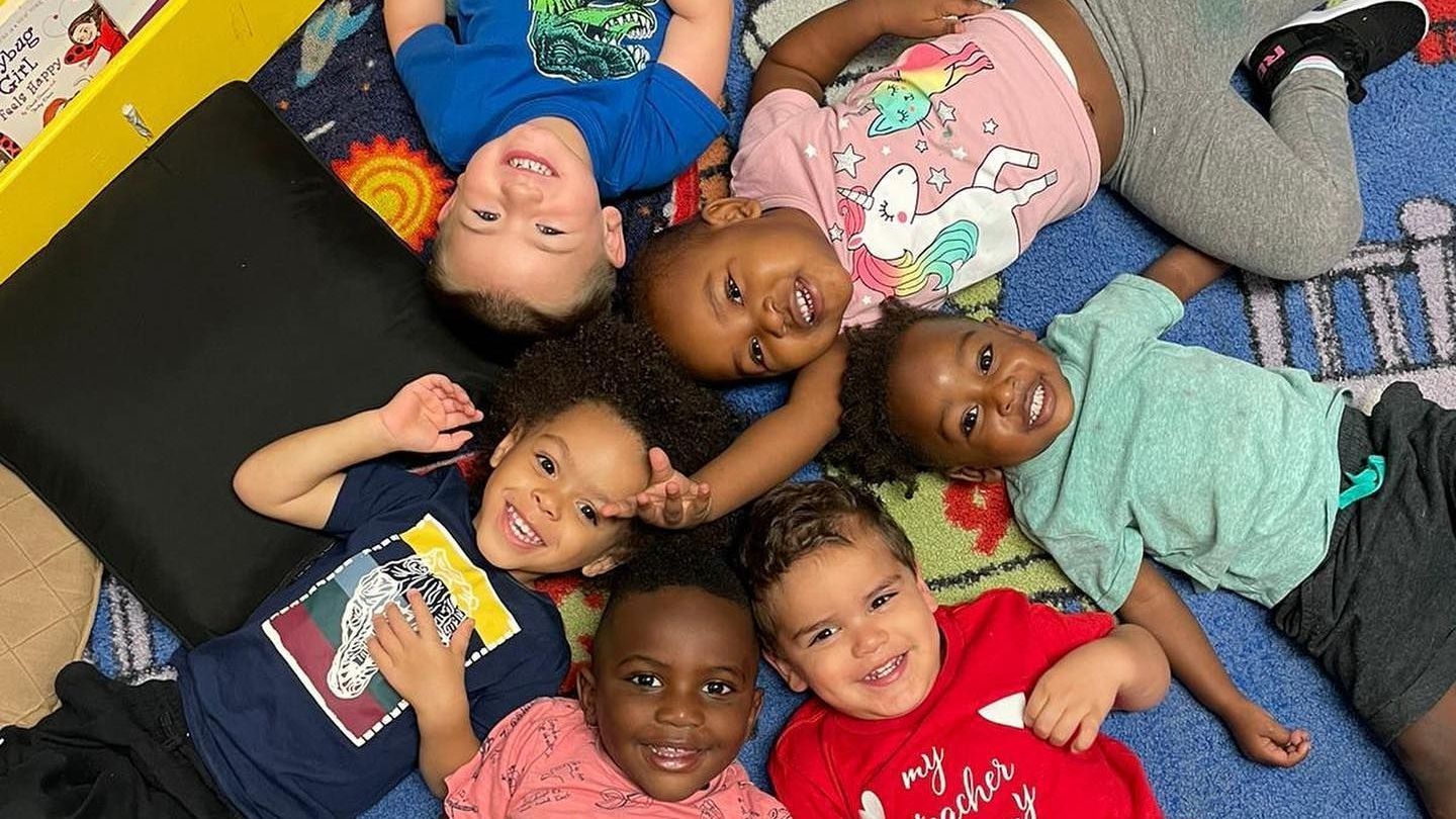 A group of children are laying on the floor in a circle.