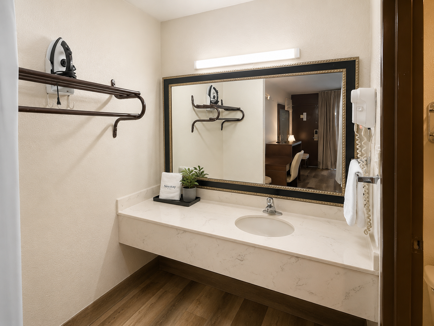 Modern restroom vanity with a long mirror, white sink, beige walls, and wooden floor.