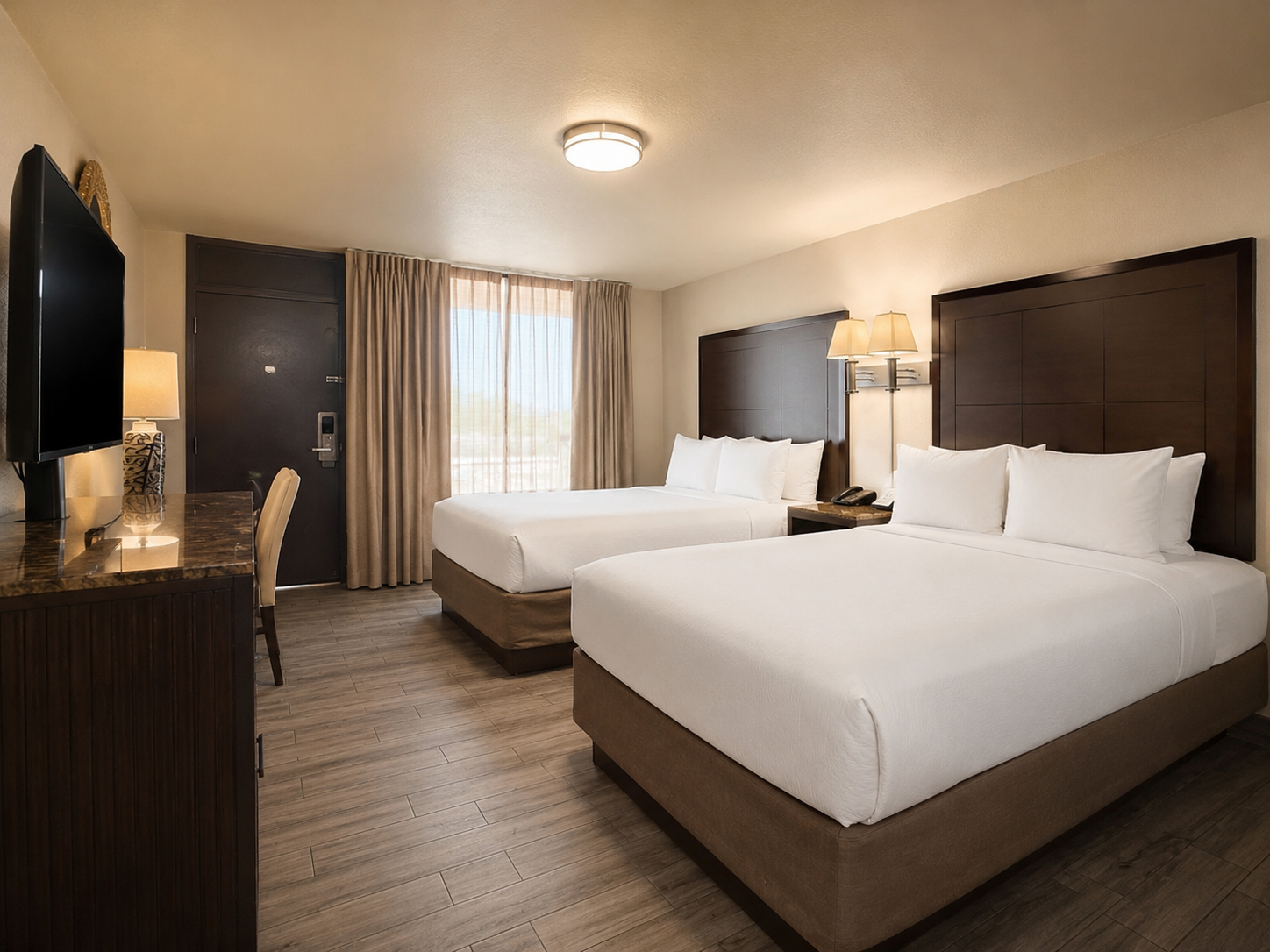 Hotel room with two white beds, dark wood furniture, and curtained windows
