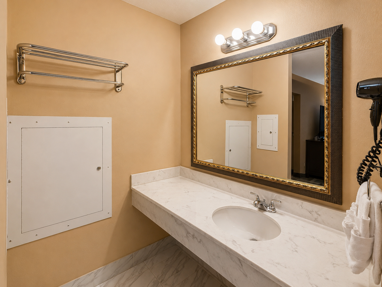 Bathroom vanity with mirror, beige walls, towel racks, and a white countertop sink.