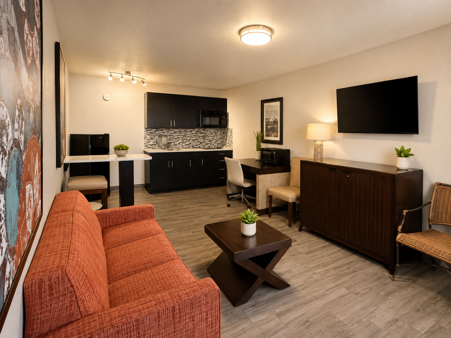 Modern living room with orange sofa, coffee table, wall-mounted TV, and small office desk nook