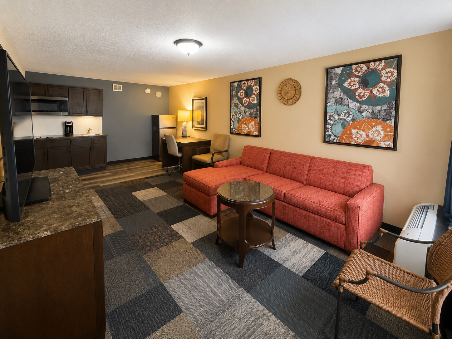Modern living room with coral sofa, patterned wall art, coffee table, and kitchenette area