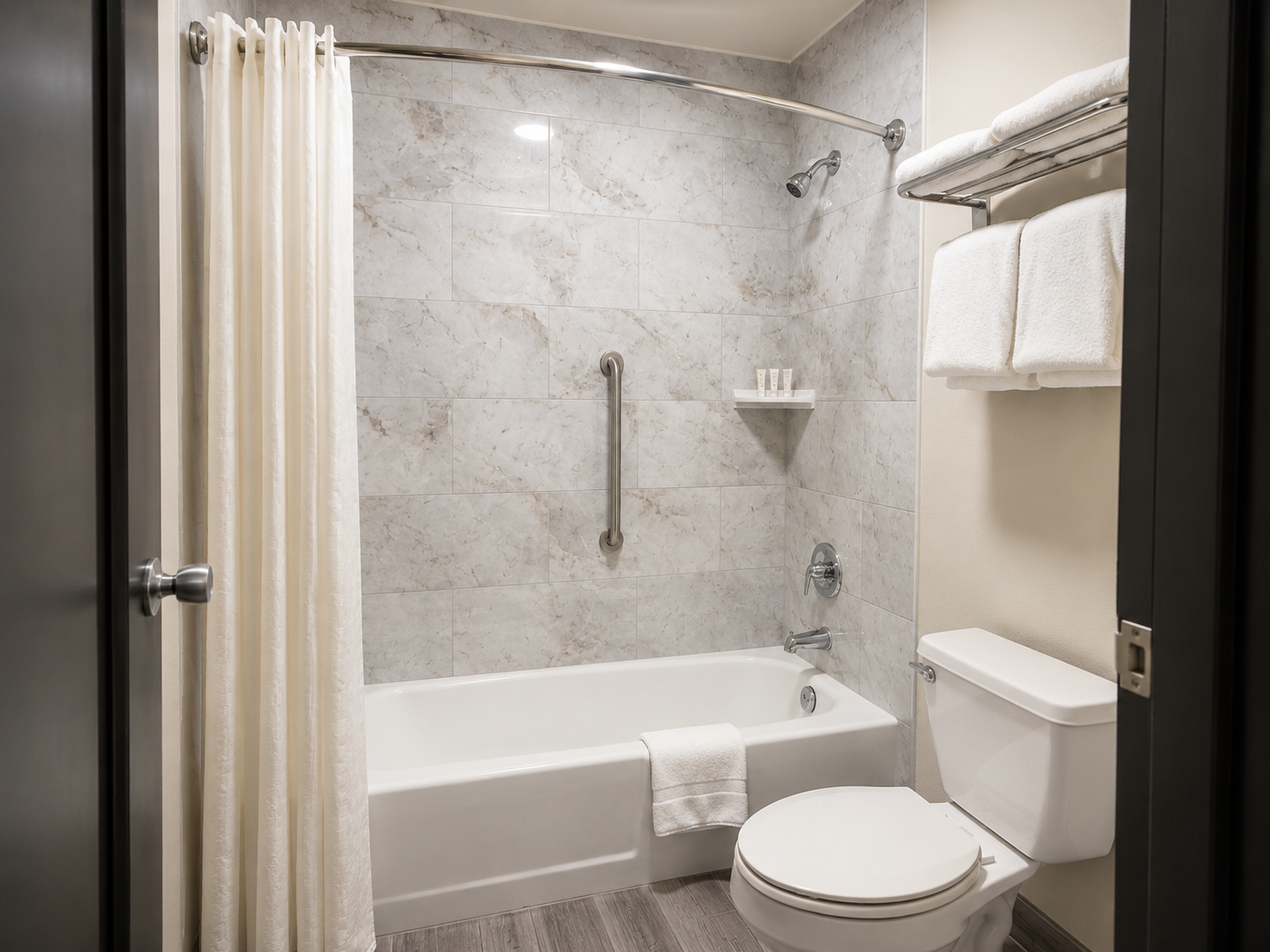 Modern bathroom with tub, shower curtain, white towels, toilet, and gray stone walls