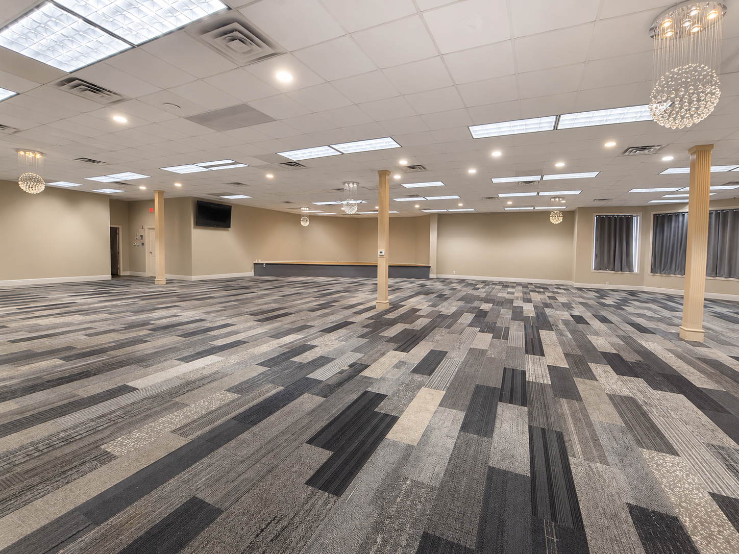 Empty carpeted conference room with gray patterned flooring, beige walls, and ceiling lights