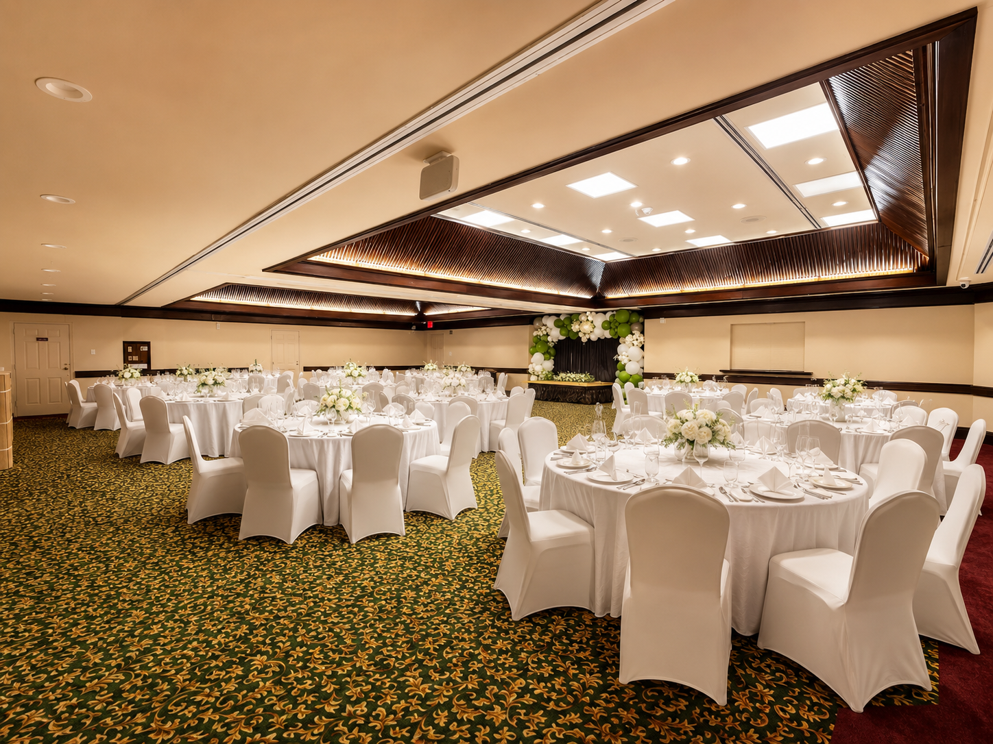 Elegant banquet hall with round white-clothed tables and chairs under warm recessed lighting