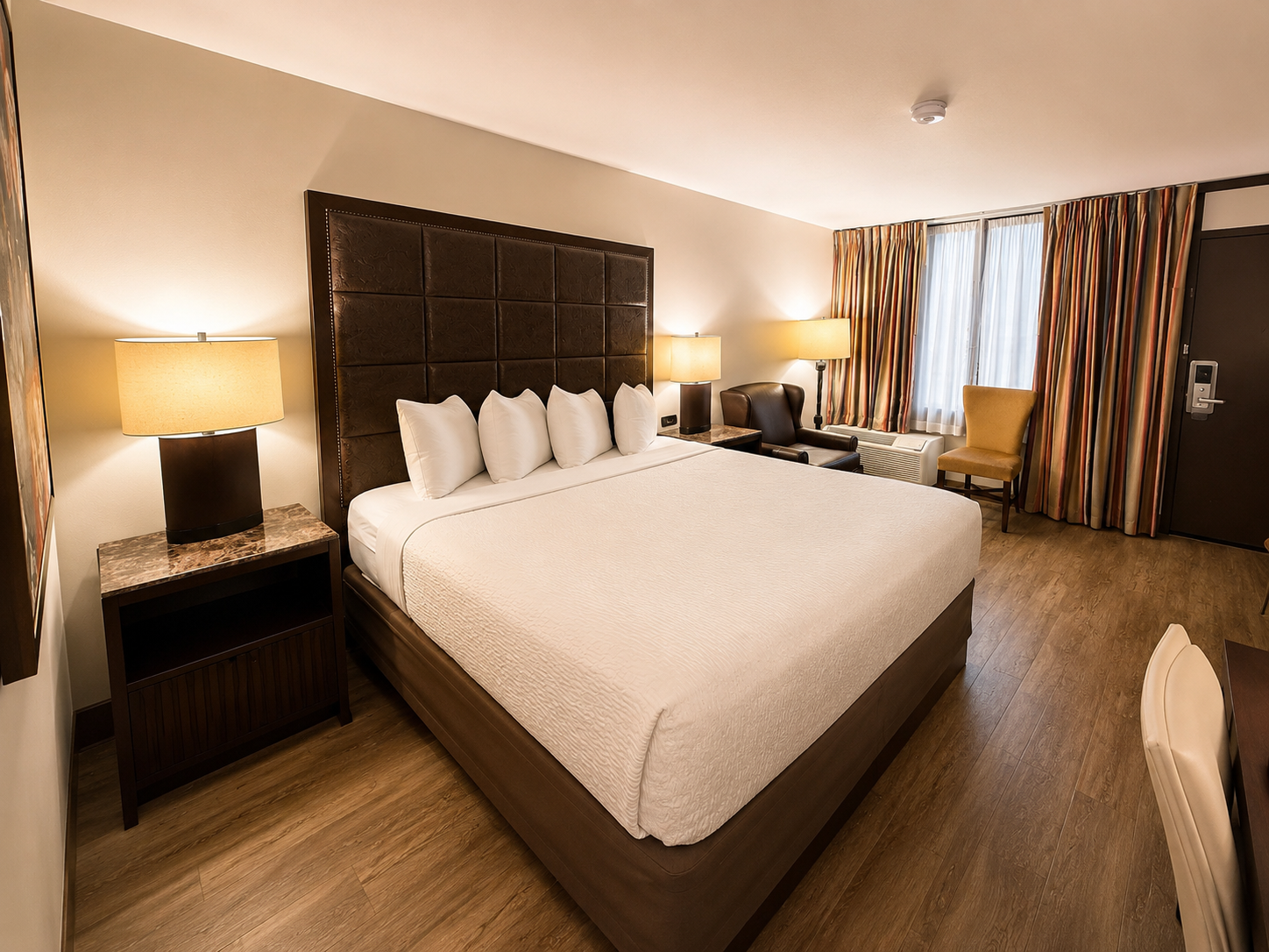 Hotel room with a large king bed, bedside lamps, window drapes, and a seating area