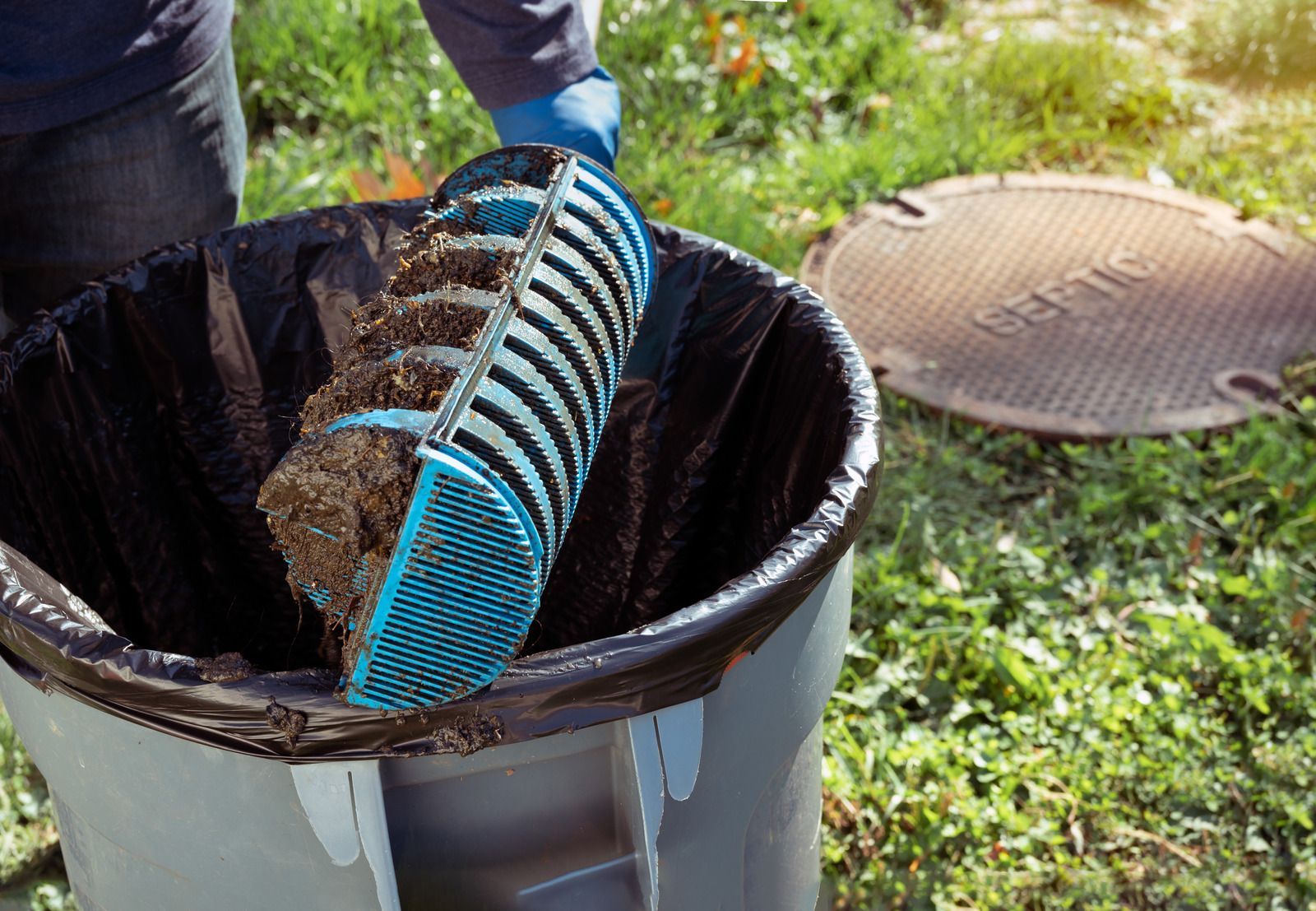 A person is cleaning a trash can with a broom.