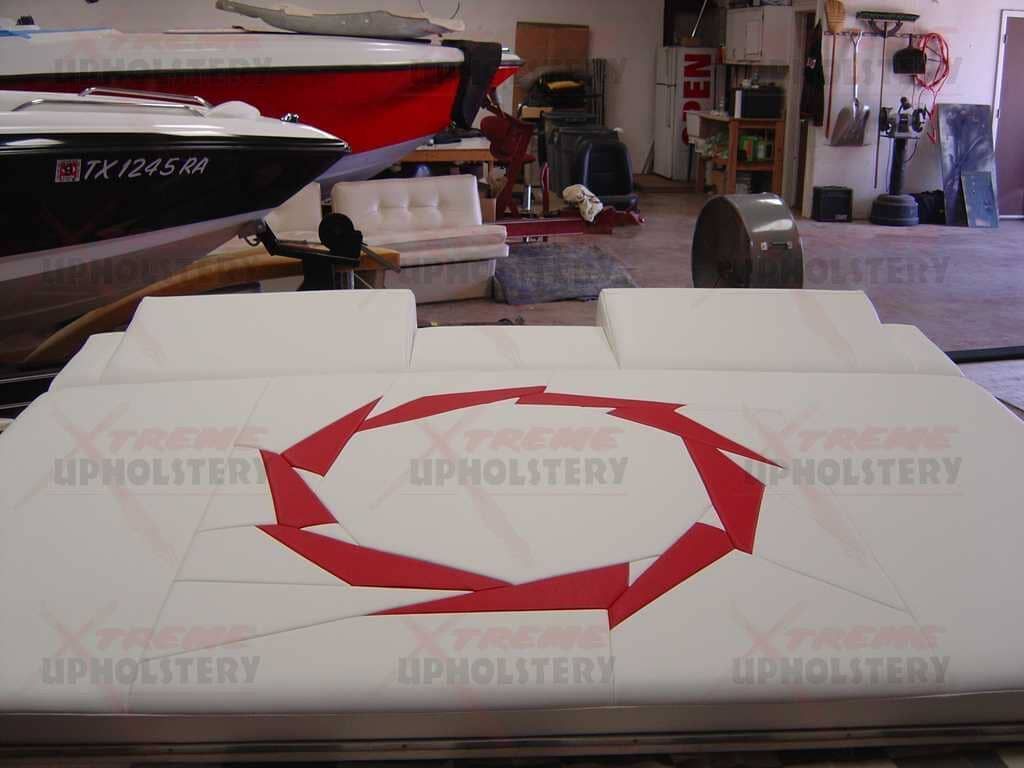 White upholstered panel with a red circular arrow logo in a workshop, with boats and tools in the background
