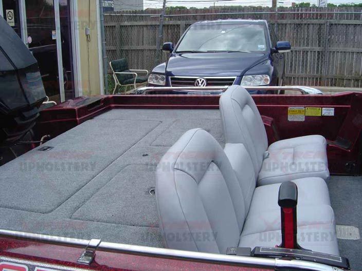 Red pickup bed lined with carpet and gray cushions, parked in a driveway with a Volkswagen behind it.