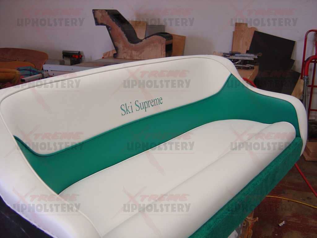 Green-and-white upholstered loveseat in a workshop or furniture showroom