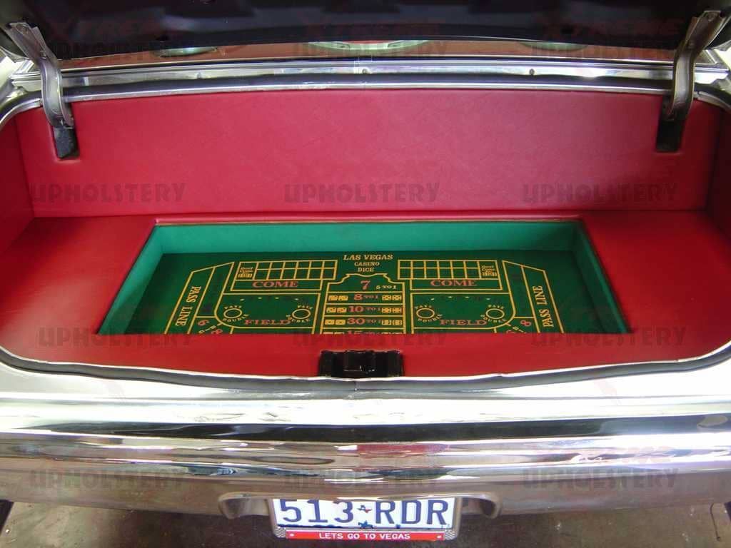 Open car trunk with a green felt, gold-lined game board inset inside.