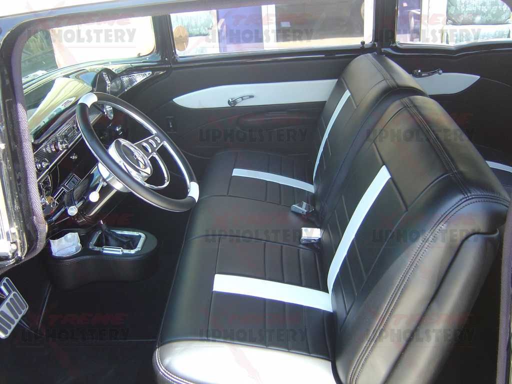 Vintage car interior with black vinyl bench seats and a chrome steering wheel