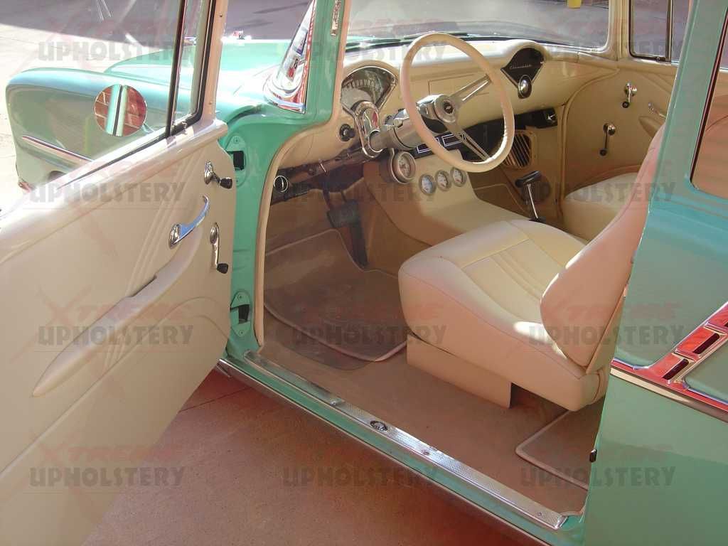 Vintage car interior with turquoise and tan upholstery, steering wheel, and open door