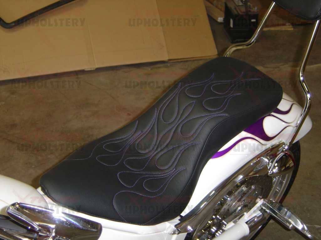 Black motorcycle seat with flame pattern and chrome bodywork against a cardboard-box background
