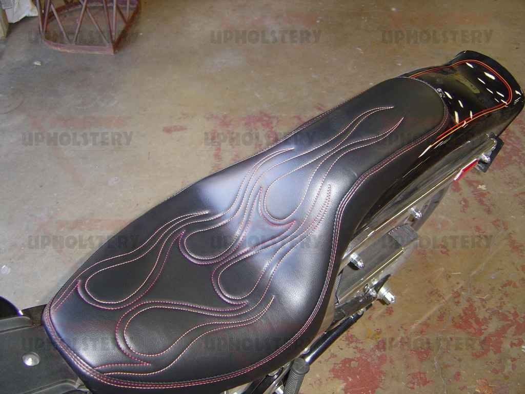Black motorcycle seat with pink stitching on a bike frame indoors