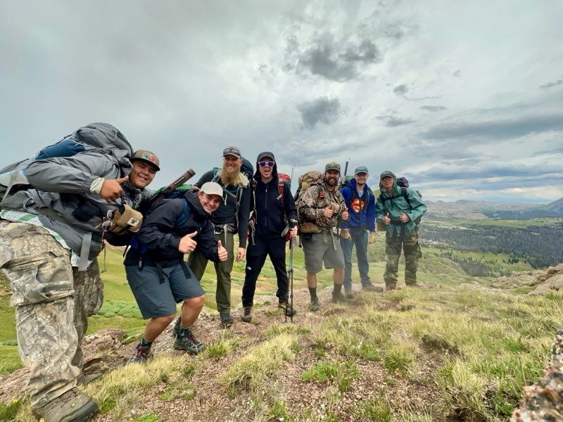 A group of young men are posing for a picture in front of a mountain.